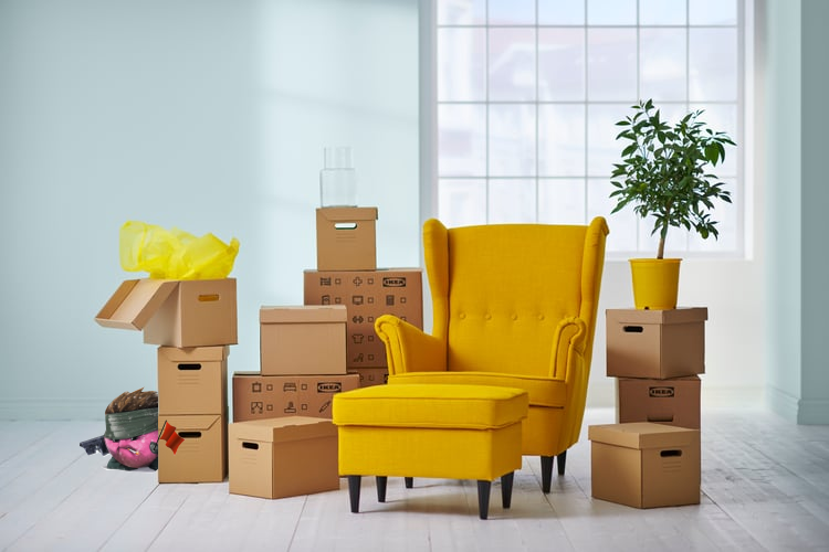 A sneaky kirby with a flag, hiding behind IKEA boxes